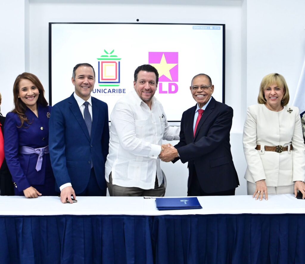 Hombres estrechando manos frente a logos de UNICARIBE y LD.