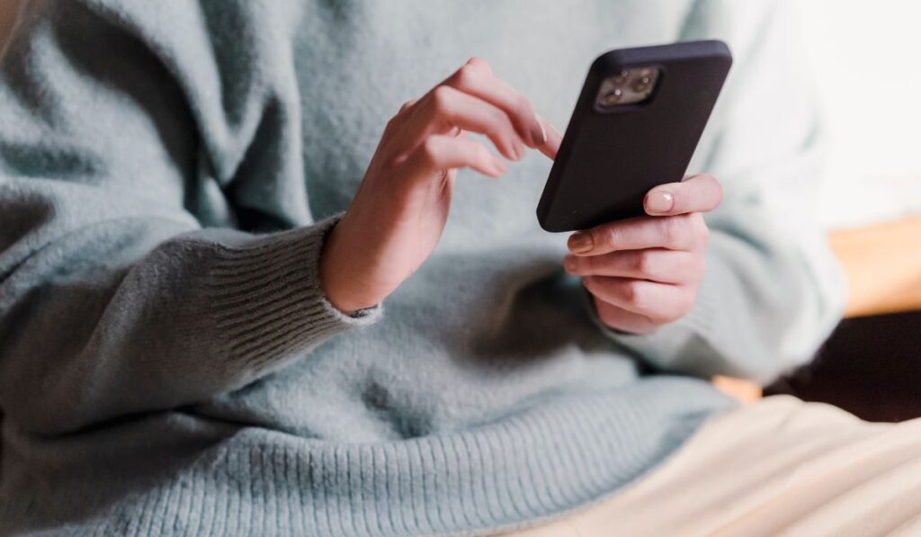Persona usando su teléfono móvil con ambas manos