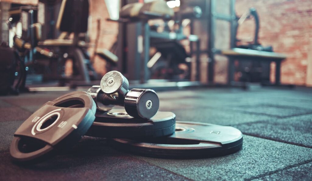 Pesas y discos en el suelo de un gimnasio vacío.
