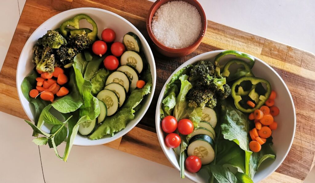 Dos boles de ensalada fresca con verduras coloridas y sal marina.