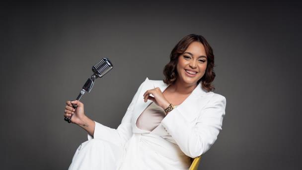 Mujer sonriente con micrófono vintage y traje blanco