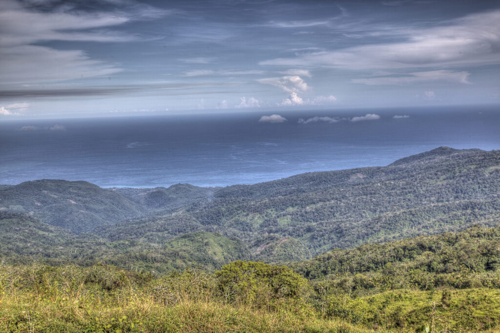 Vista panorámica de montañas verdes que descienden hacia el océano.