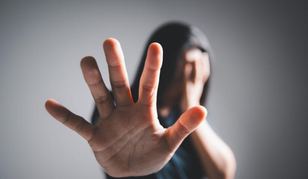 Mano extendida pidiendo detenerse, persona oculta detrás.