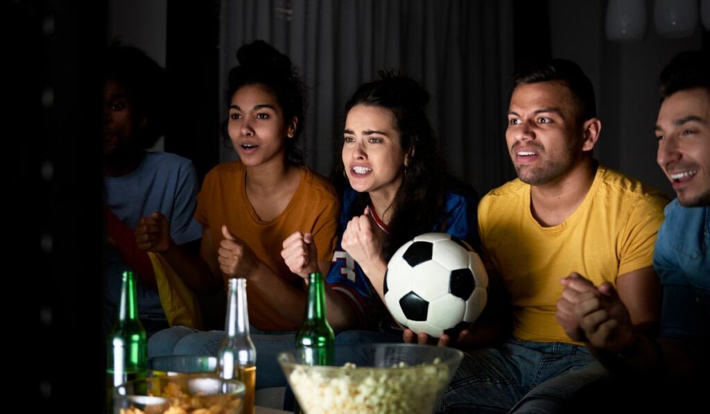 Grupo de amigos viendo un partido de fútbol con emoción.