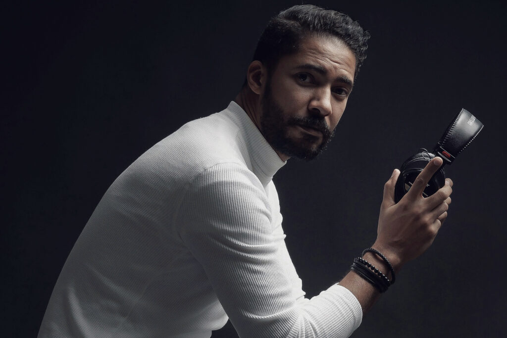 Hombre con auriculares y jersey blanco con cuello alto.