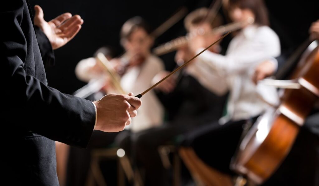 Director de orquesta dirigiendo con una batuta a músicos