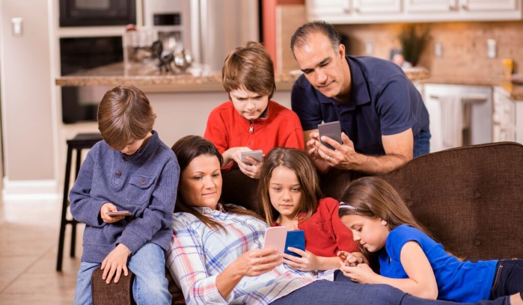 Familia en el sofá usando teléfonos móviles, cada uno absorto.