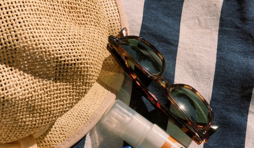 Accesorios de playa: sombrero, gafas de sol y protector solar.
