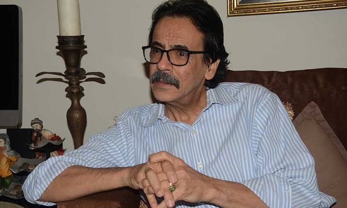 Hombre de mediana edad con gafas y bigote sentado.