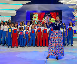 Cantante principal dirigiendo a un coro de niños en un escenario.