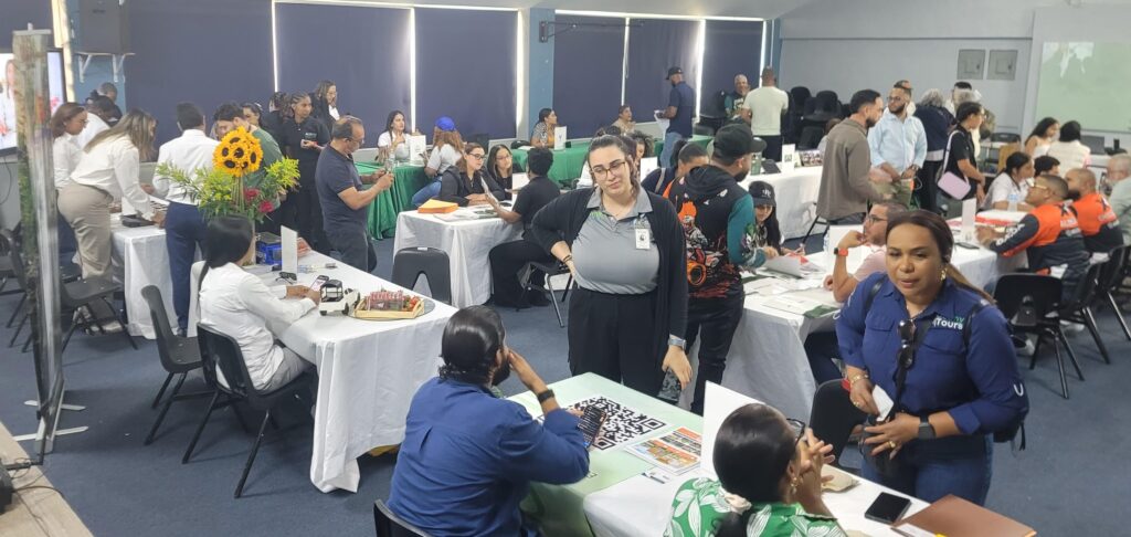 Gente interactuando en un evento o feria informativa con mesas y expositores.