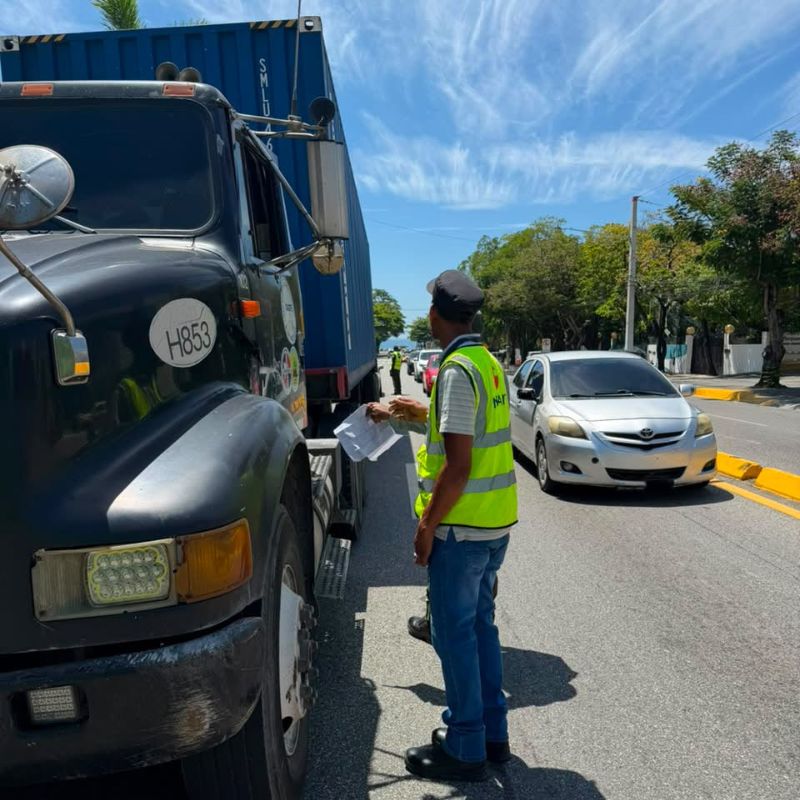 Agente de tránsito inspecciona camión con contenedor en la carretera.