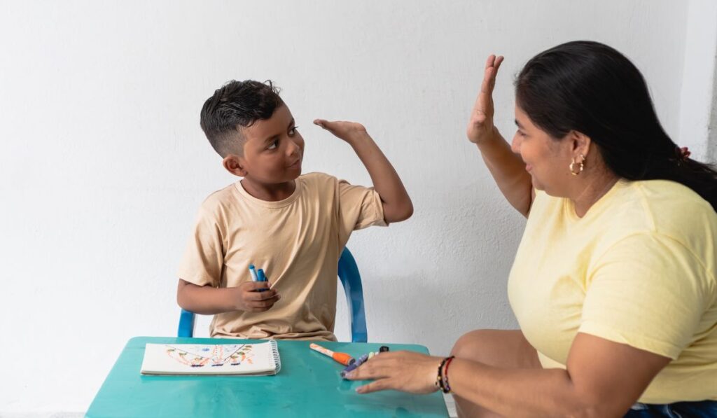 Niño y mujer se dan la mano en señal de éxito.