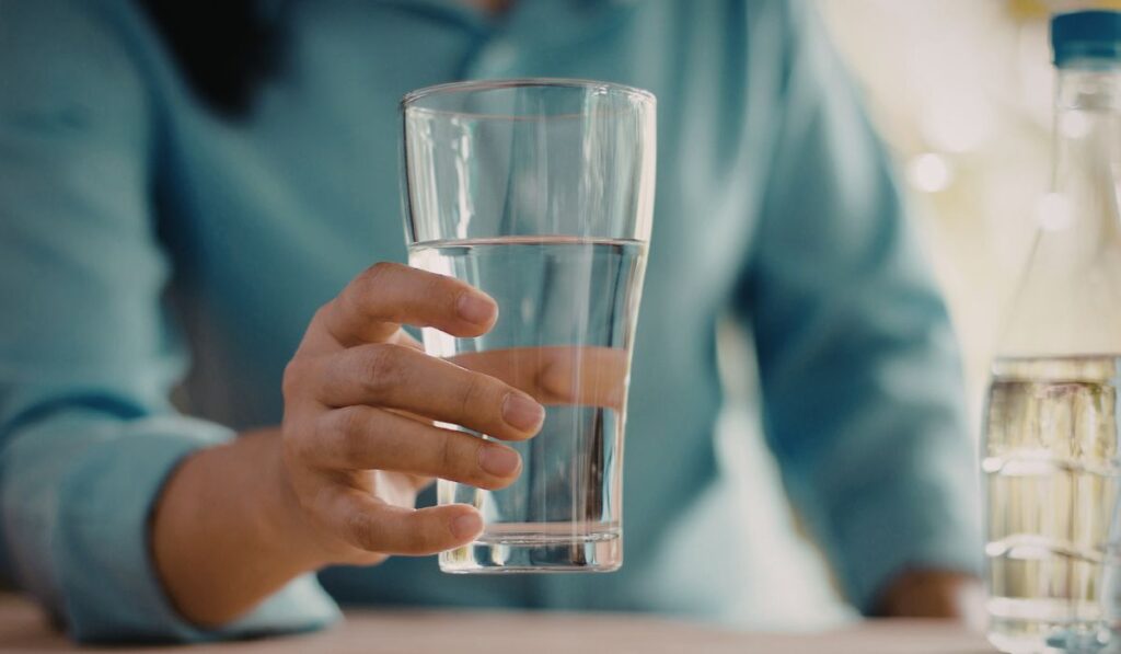 Persona sujetando un vaso de agua transparente