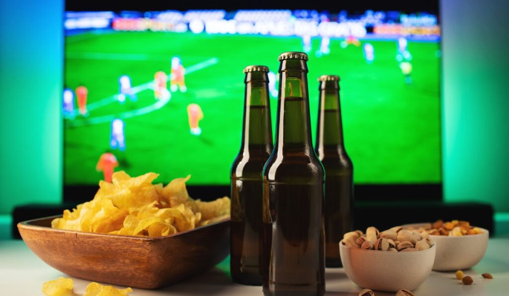 Cervezas y aperitivos viendo un partido de fútbol en la televisión.
