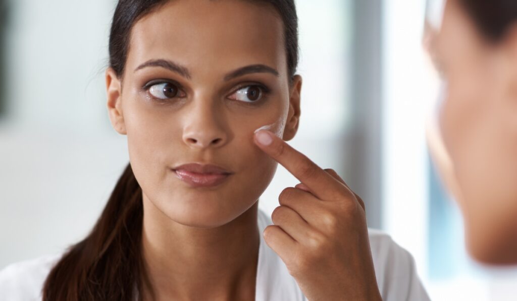 Mujer aplicándose crema facial con el dedo índice.