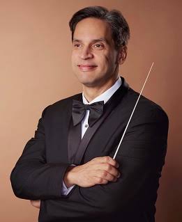Director de orquesta con corbata de lazo y batuta.