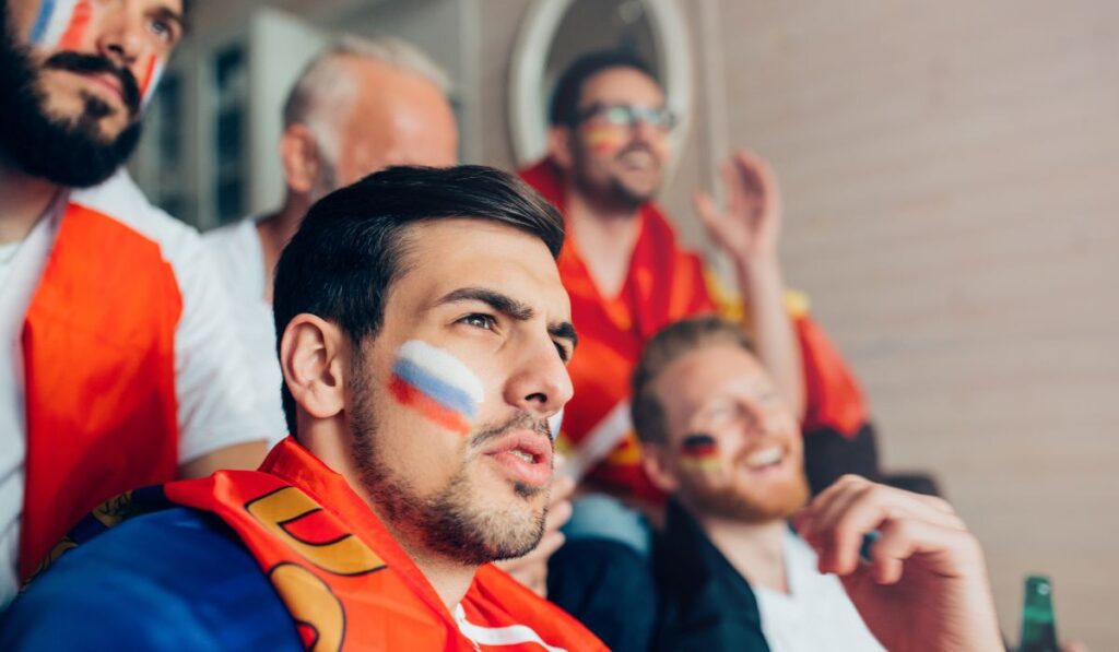 Aficionados viendo un partido con la cara pintada.