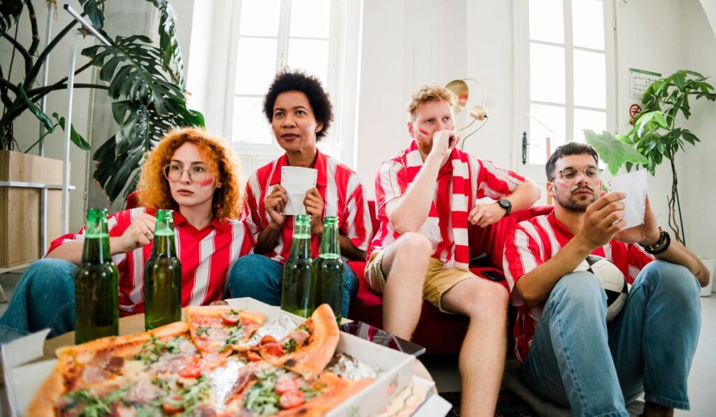 Aficionados con camisetas a rayas rojas y blancas viendo partido.