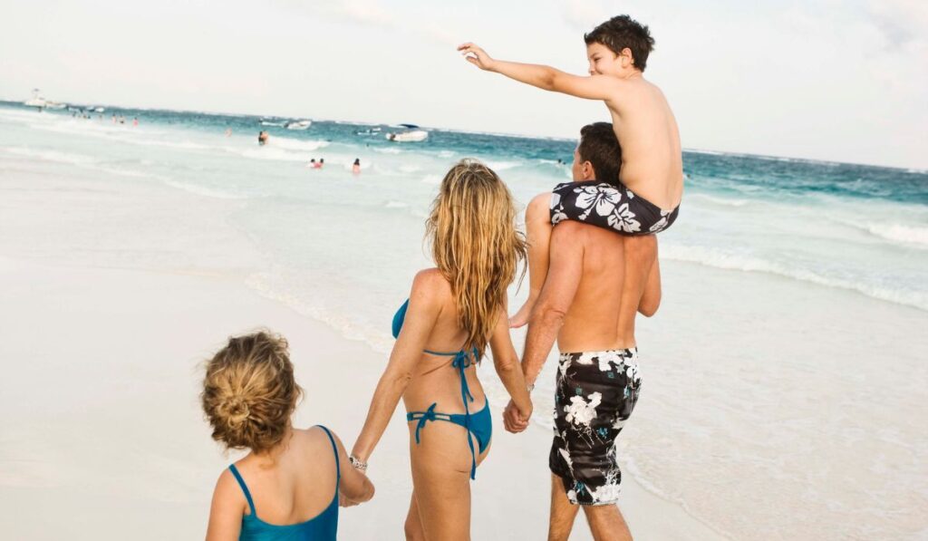 Familia paseando por la playa disfrutando del mar.