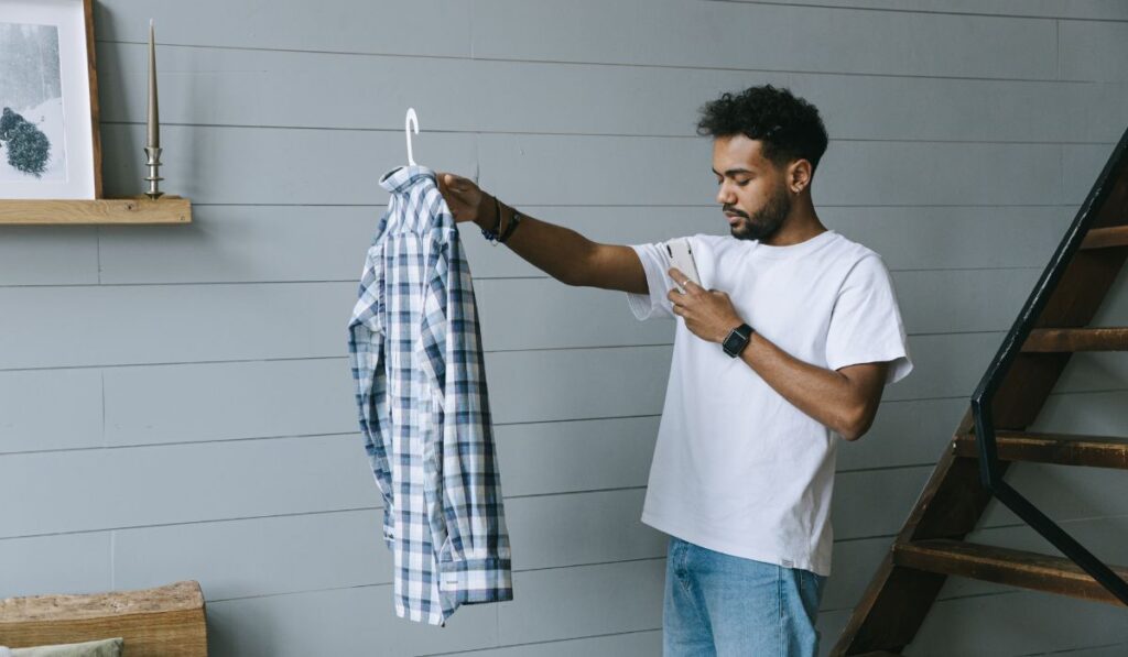 Hombre con camisa a cuadros mira su teléfono móvil.