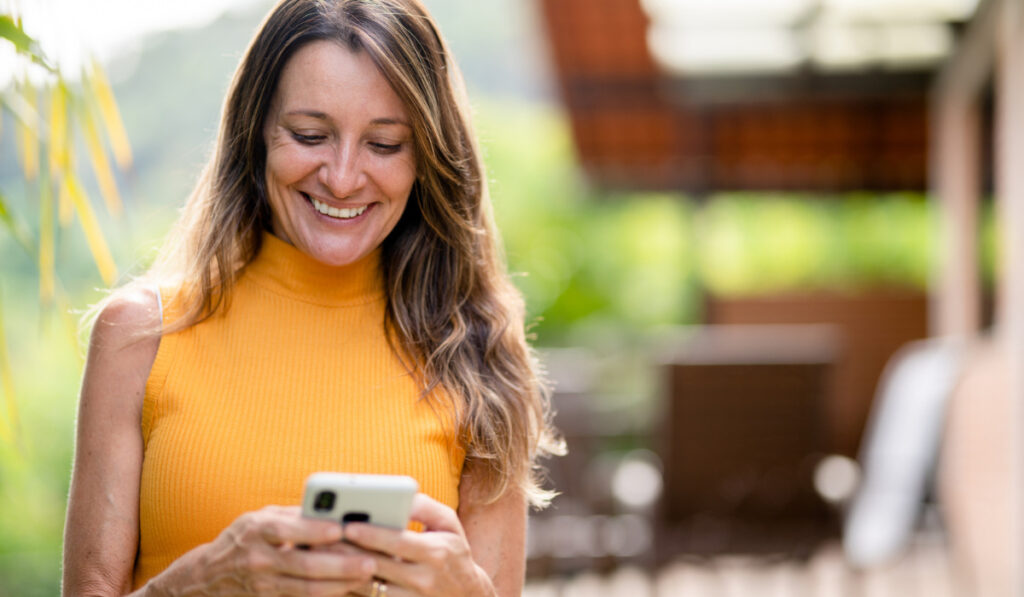Mujer sonriendo mientras mira su teléfono móvil